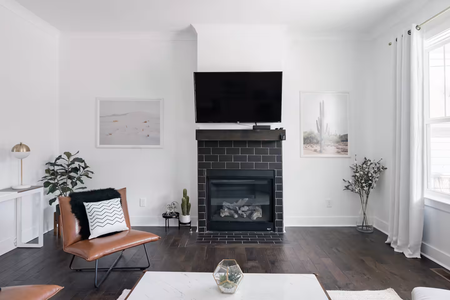 Living room with a black tile gas fireplace, leather chair and dark walnut floors